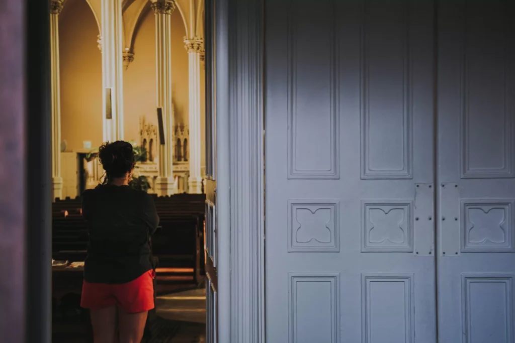 Person standing in the back of a church to represent religious trauma in texas