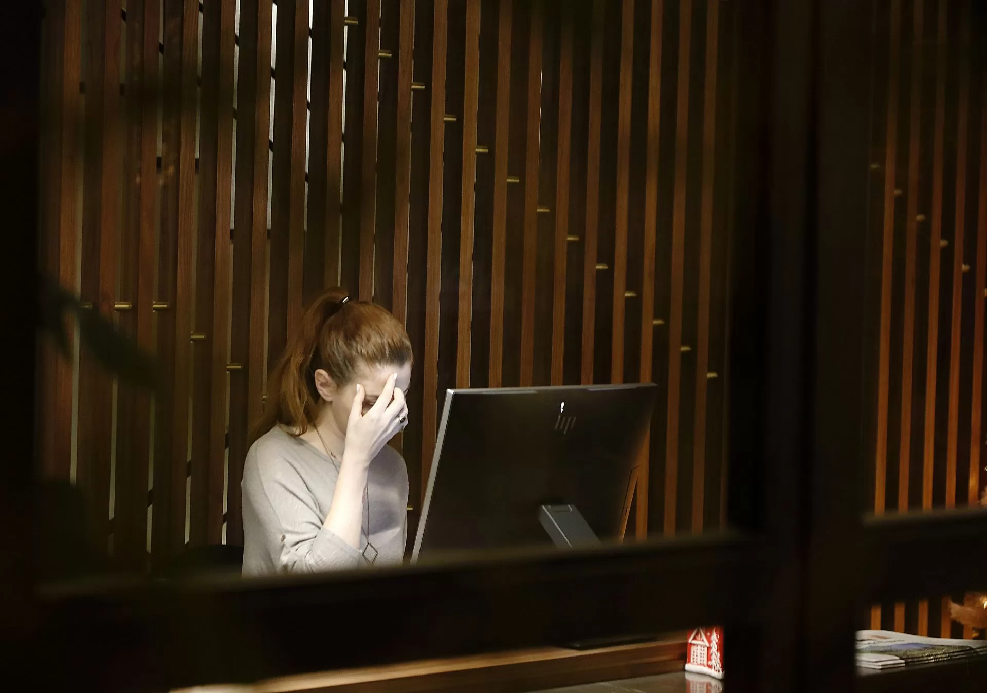 Woman looking tired in front of a computer to depict how religious trauma shows up at work