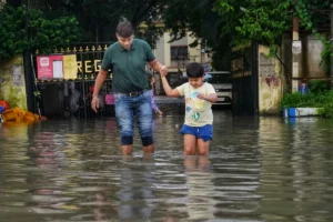 An image of a man and a child holding hands as they walk through a flooded street to represent climate change trauma