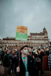 Image of man at protest holding sign read "it's capitalism vs the planet" to represent climate change therapy